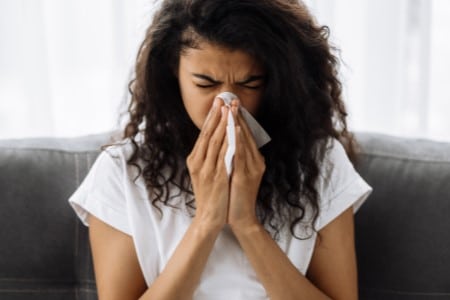 Jeune femme allergique se mouchant le nez