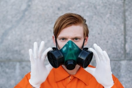 Homme en combinaison orange et gants blanc porte un demi masque de protection respiratoire