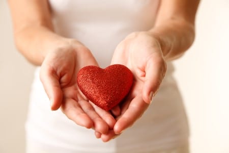 Concept de don pour une association : femme offrant son coeur au creux des mains