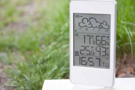 Ecran d'une station météorologique posée sur l'herbe affichant les conditions météo