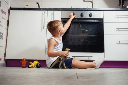 Enfant jouant avec une cuisinière à gaz dans la cuisine