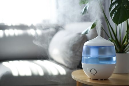 Humidificateur d'air de couleur bleu diffusant une brume légère dans la maison