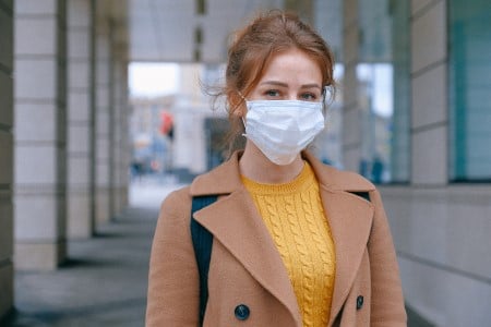 Jeune femme brune portant un masque chirurgical à l'extérieur