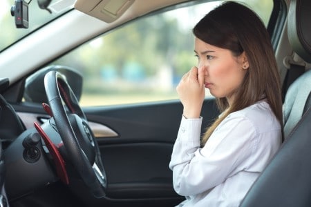 Jeune femme se bouchant le nez à cause d'une odeur de moisissure dans la voiture